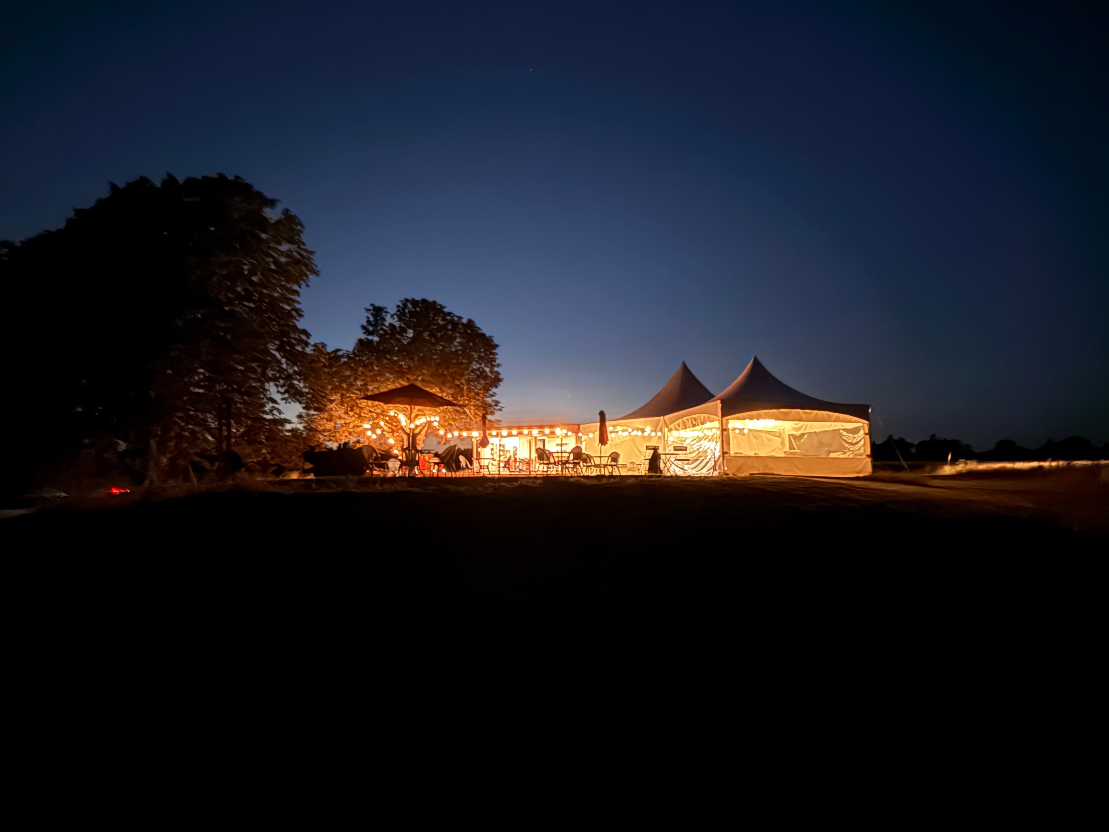 Double Hill Cidery tent glowing at night, reflected in still water